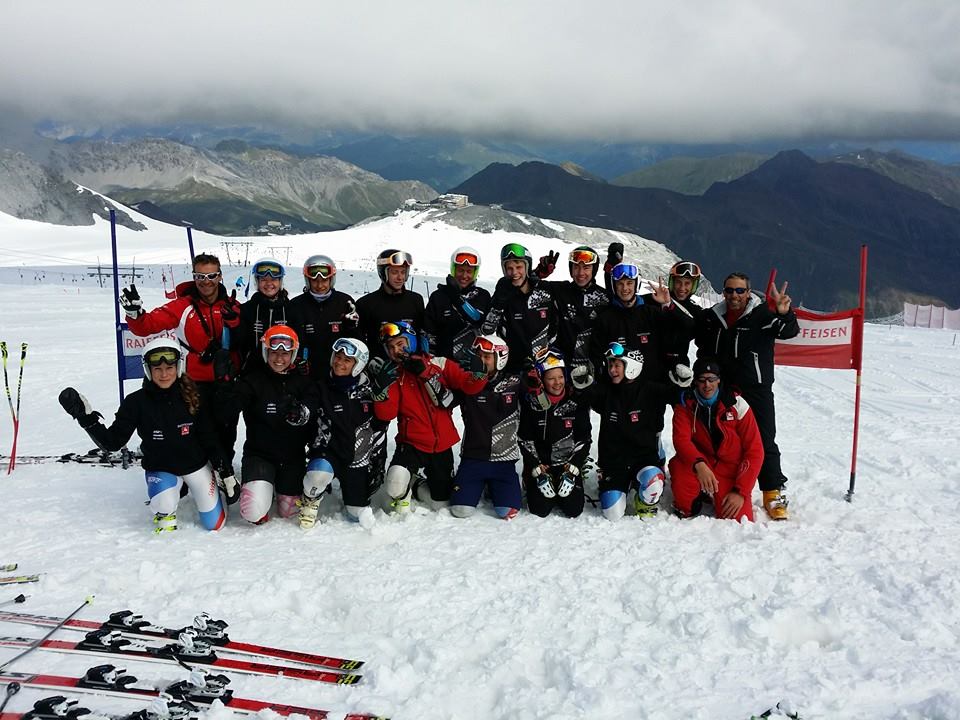 Un gruppo di sportivi posa sulla neve con gli sci